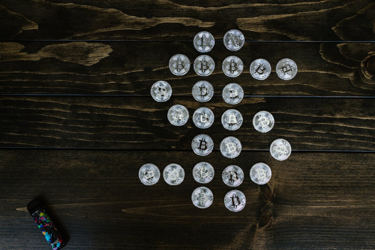 Flat lay of Bitcoin coins arranged in a shape on a wooden surface representing digital currency.